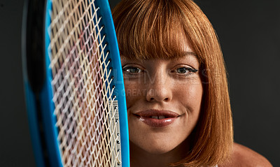 Buy stock photo Shot of a young woman posing with a tennis racket against a dark background