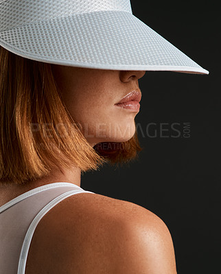 Buy stock photo Cropped shot of a sporty young woman wearing a sun visor against a dark background