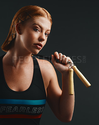 Buy stock photo Studio portrait of a sporty young woman posing with a skipping rope against a black background