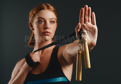 Buy stock photo Studio shot of a sporty young woman posing with a skipping rope against a black background