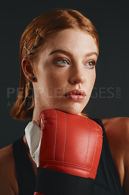 Buy stock photo Studio shot of a sporty young woman wearing boxing gloves against a black background