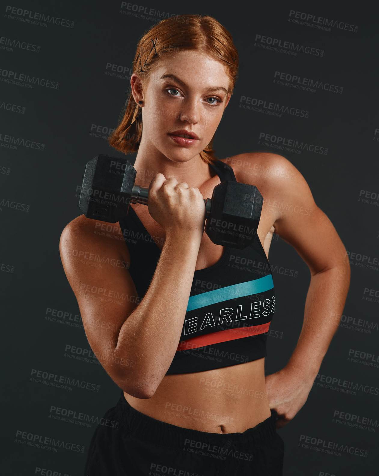 Buy stock photo Studio portrait of a sporty young woman exercising with a dumbbell against a black background