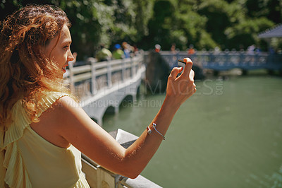 Buy stock photo Shot of a young woman taking pictures of a river in Vietnam with her smartphone
