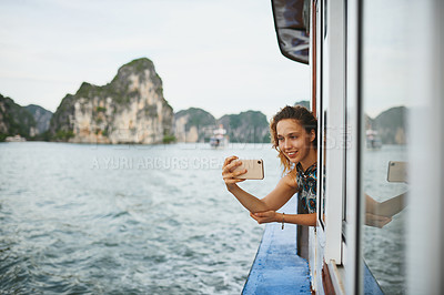 Buy stock photo Shot of a young woman taking selfies on a boat ride in Vietnam with her smartphone