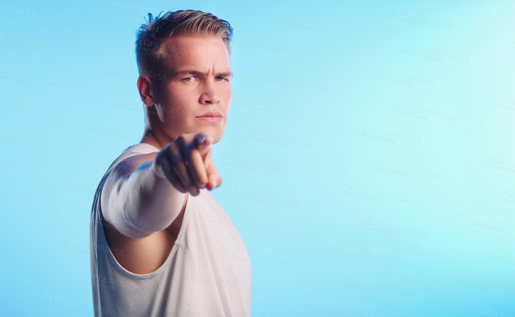 Buy stock photo Studio portrait of a handsome young man pointing against a blue background