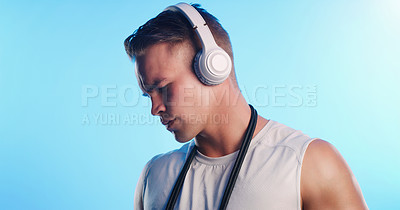Buy stock photo Studio shot of a young man posing with a skipping rope and headphones against a blue background