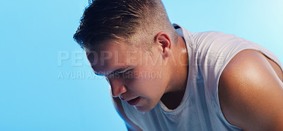 Buy stock photo Studio shot of a handsome young man hunched over against a blue background