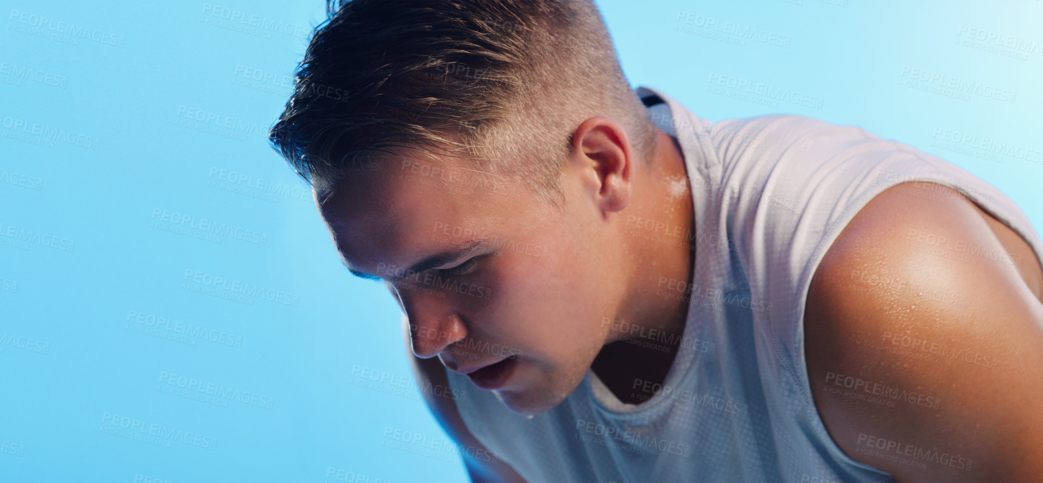 Buy stock photo Studio shot of a handsome young man hunched over against a blue background
