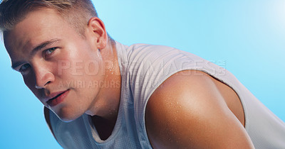 Buy stock photo Studio portrait of a handsome young man hunched over against a blue background