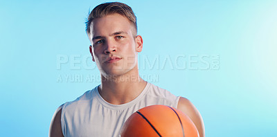 Buy stock photo Studio portrait of a handsome young male basketball player posing with a ball against a blue background