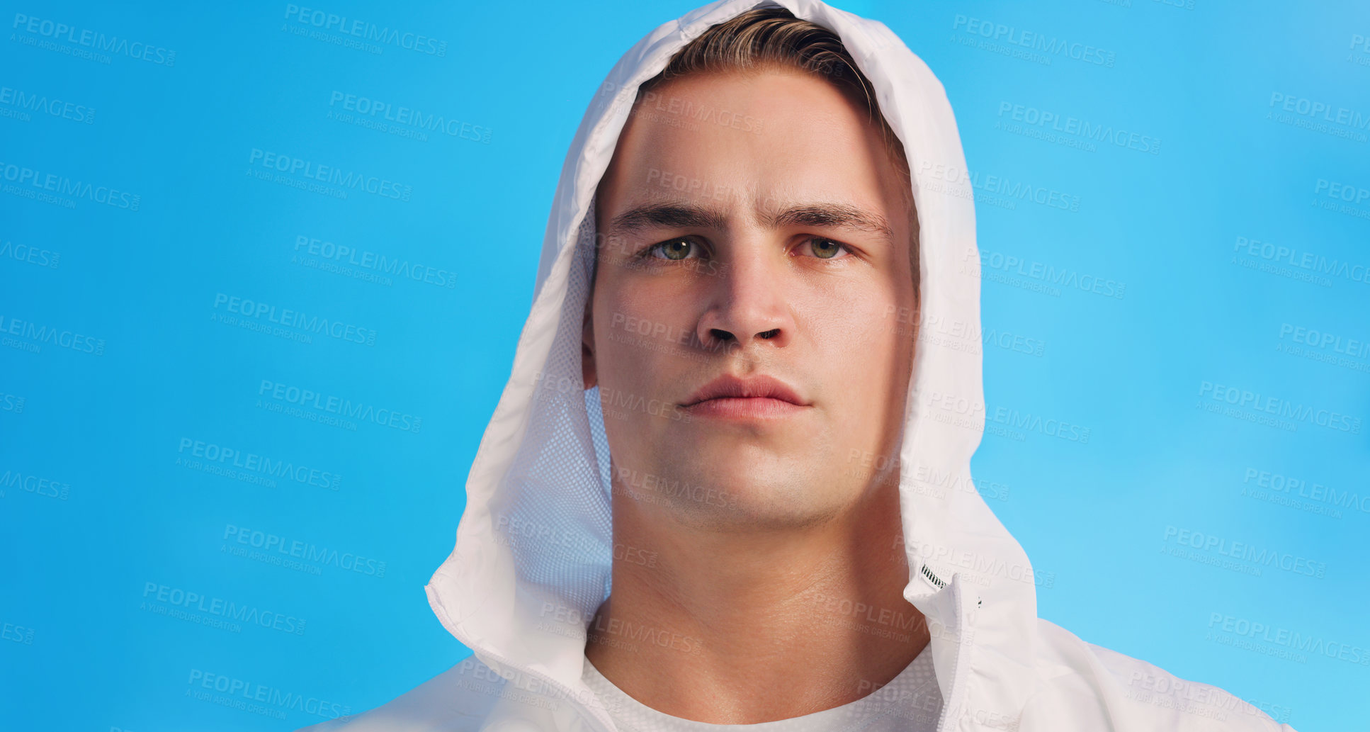 Buy stock photo Studio portrait of a handsome young man posing in a hooded sweater against a blue background