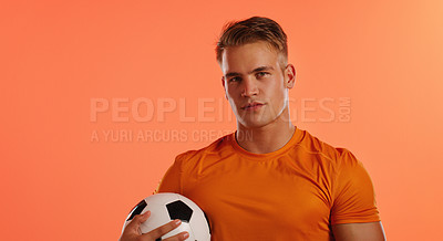 Buy stock photo Studio portrait of a handsome young male soccer ball player posing with a ball against an orange background