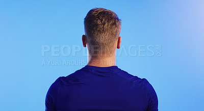 Buy stock photo Rearview shot of an unrecognizable young man posing against a blue background