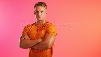 Buy stock photo Studio portrait of a handsome young man posing with his arms crossed against a peach background