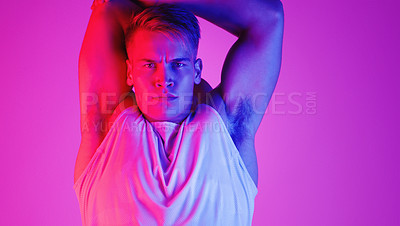 Buy stock photo Studio portrait of a handsome young man stretching against a purple background