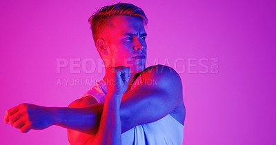 Buy stock photo Studio shot of a handsome young man stretching against a purple background