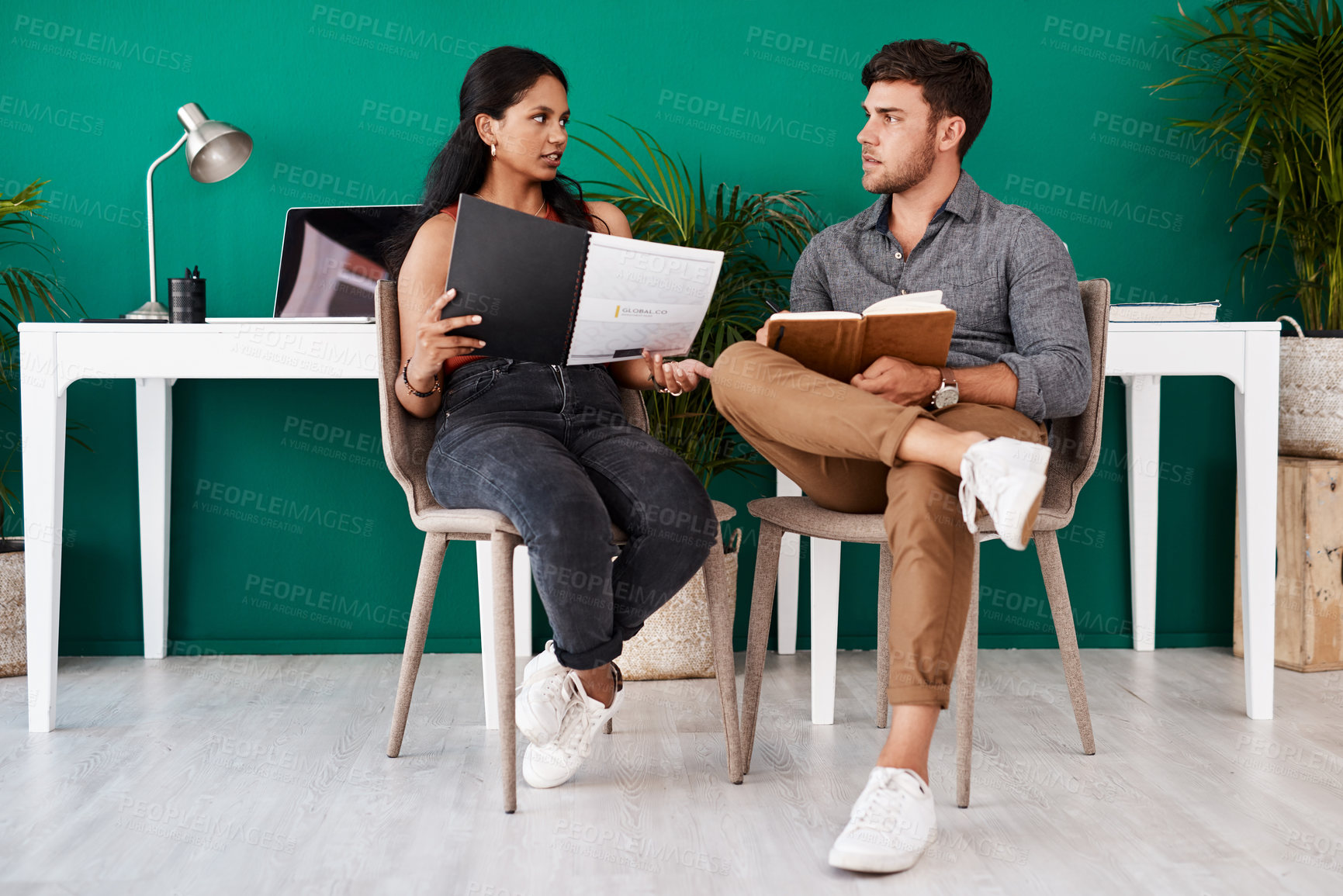 Buy stock photo Shot of two young designers having a discussion in an office