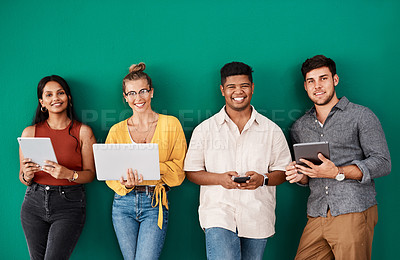 Buy stock photo Portrait of a group of young designers using digital devices while standing together against a green background
