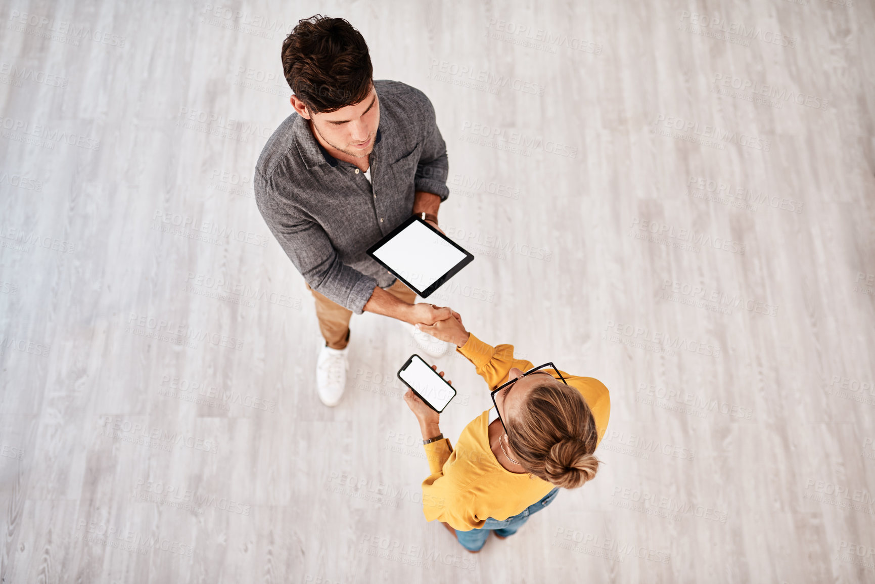 Buy stock photo Business people, handshake or meeting with technology above for online application or survey at office. Top view, businessman and woman shaking hands with tablet, phone screen or mockup for agreement