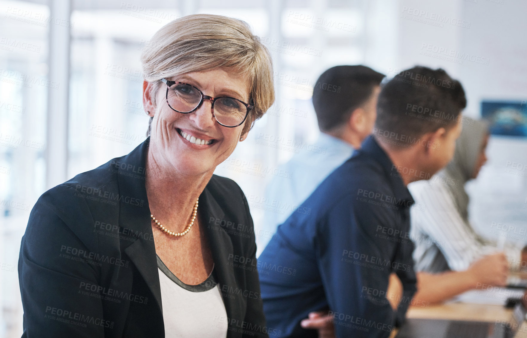 Buy stock photo Portrait of a mature businesswoman having a meeting with colleagues in a modern office