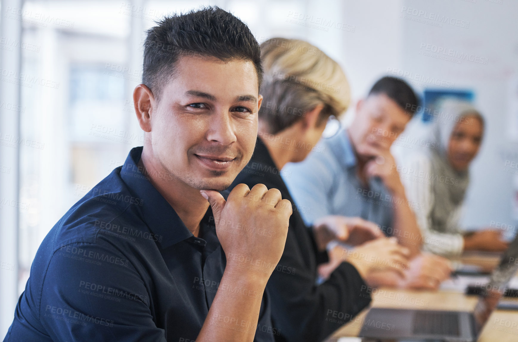 Buy stock photo Portrait of a young businessman having a meeting with colleagues in a modern office