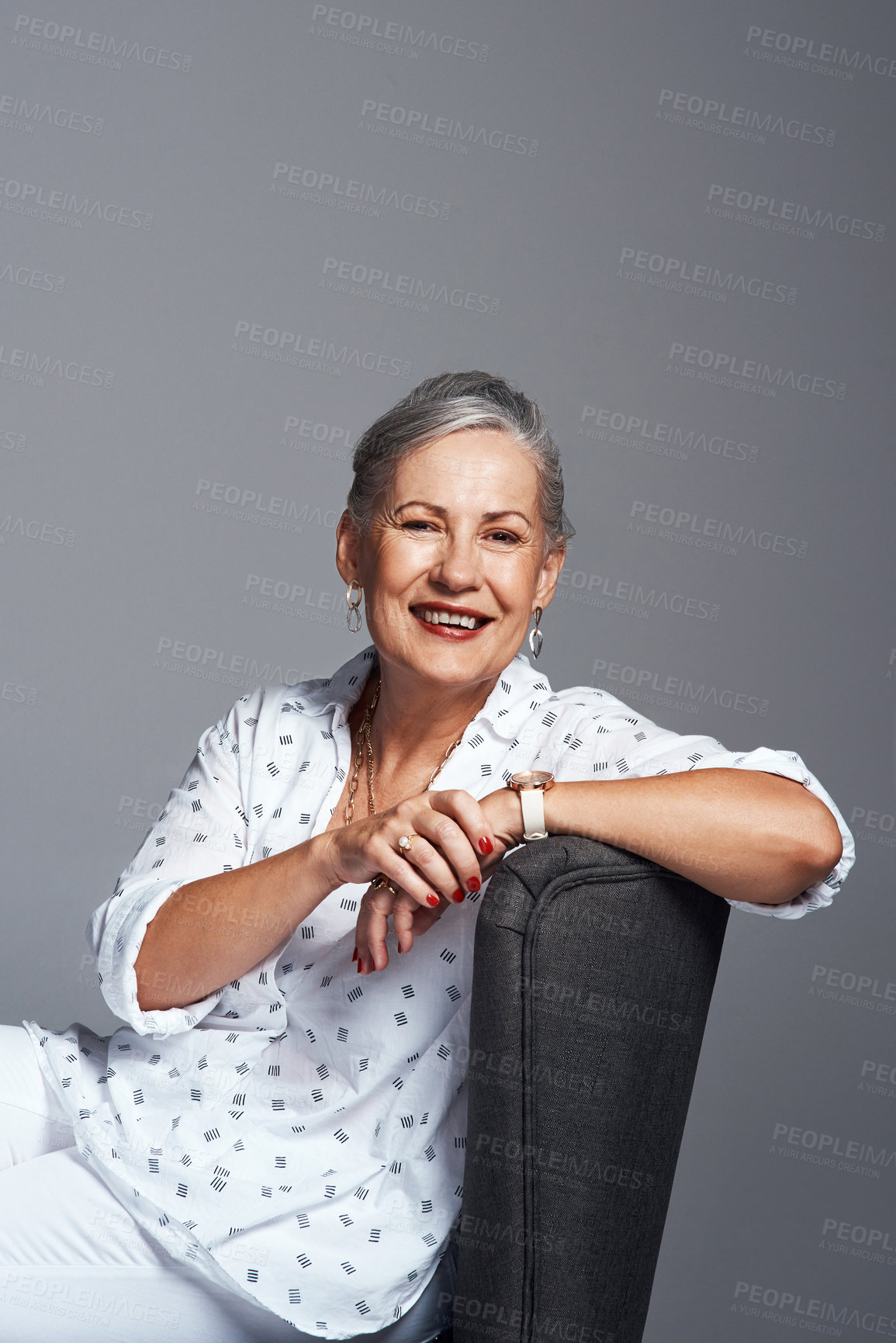 Buy stock photo Studio shot of a senior woman sitting on a chair against a grey background