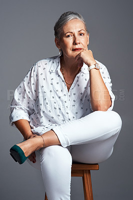 Buy stock photo Studio shot of a senior woman sitting on a chair against a grey background