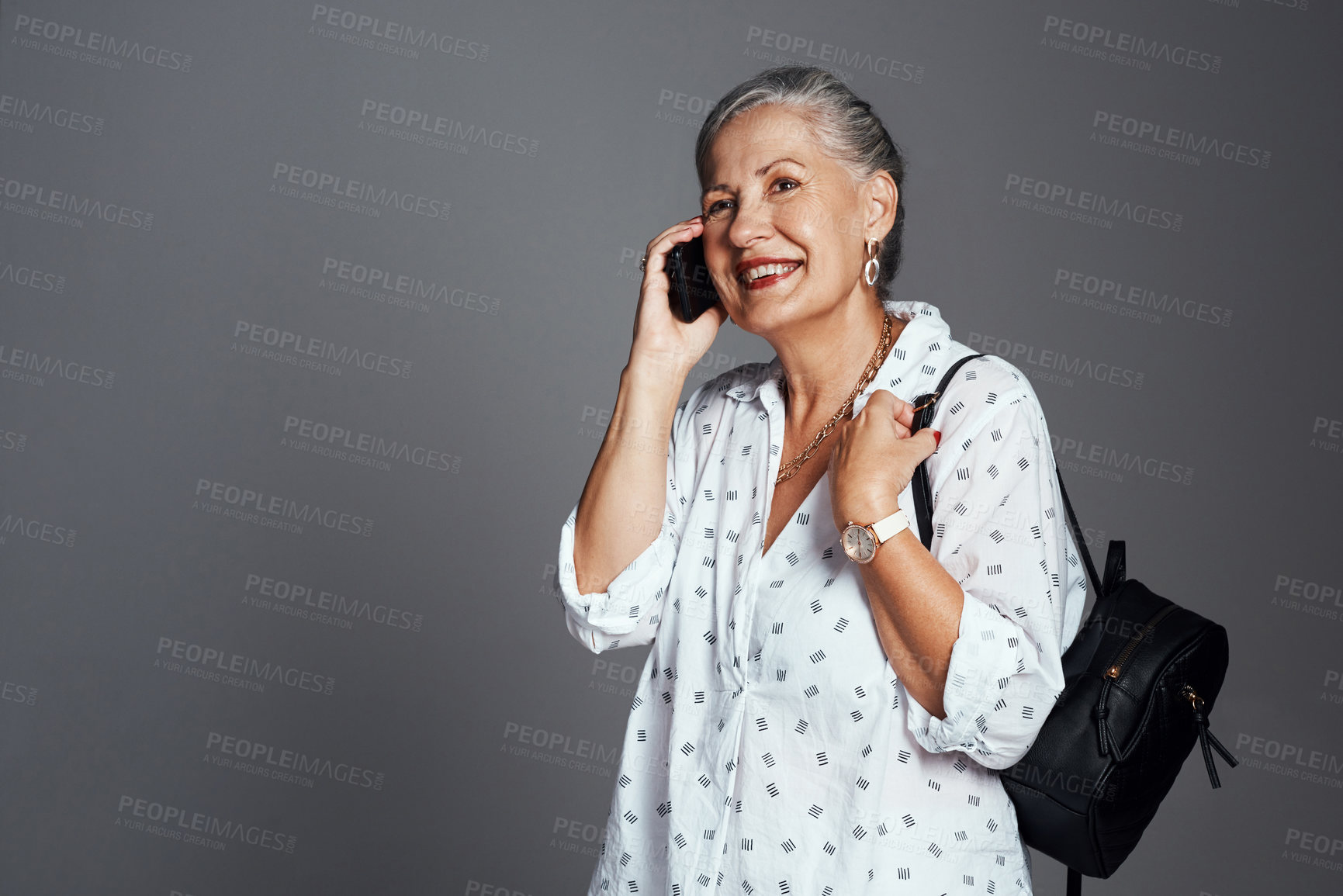 Buy stock photo Cropped shot of a senior woman carrying her handbag while talking on her cellphone