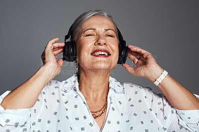 Buy stock photo Studio shot of a senior woman wearing headphones while listening to music against a grey background