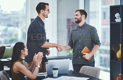 Buy stock photo Shot of two young designers shaking hands during a meeting in an office