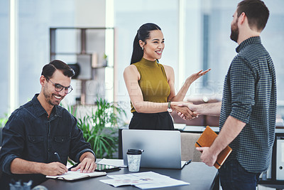 Buy stock photo Shot of two young designers shaking hands during a meeting in an office