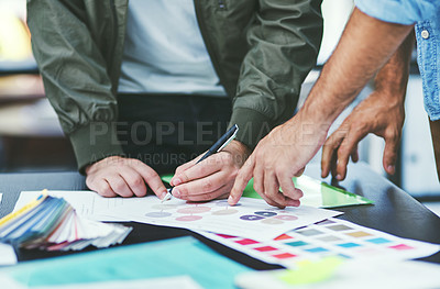 Buy stock photo Closeup shot of two unrecognisable designers going through paperwork together in an office