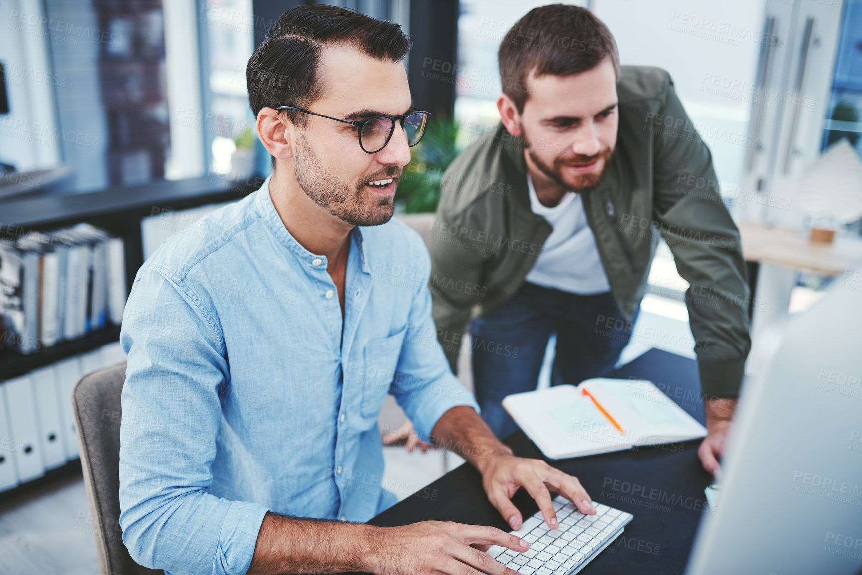 Buy stock photo Shot of two young designers working together on a computer in an office