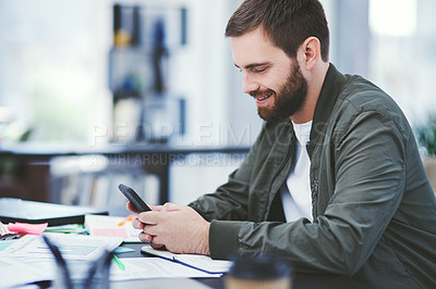 Buy stock photo Shot of a young designer using a cellphone in an office