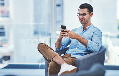 Buy stock photo Shot of a young designer using a cellphone in an office