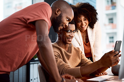 Buy stock photo Shot of a man showing his colleagues something on his cellphone