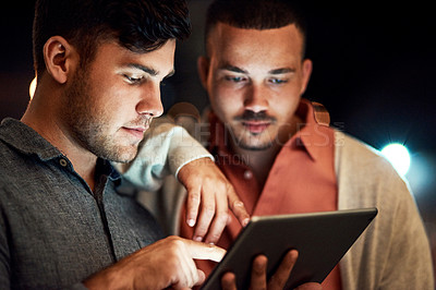 Buy stock photo Cropped shot of two businessmen looking at a digital tablet while standing outside at night