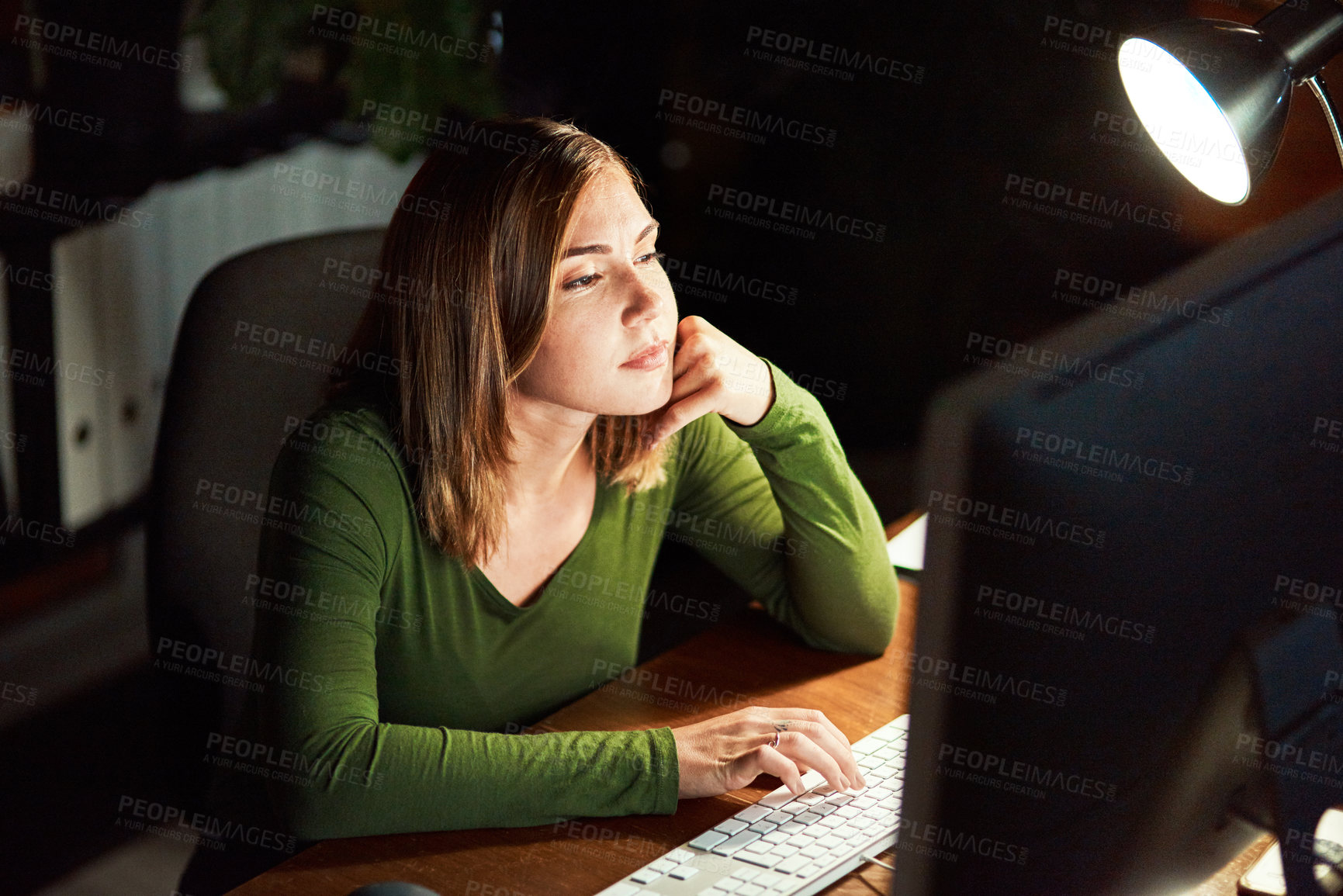 Buy stock photo Cropped shot of a young woman using her computer while working late