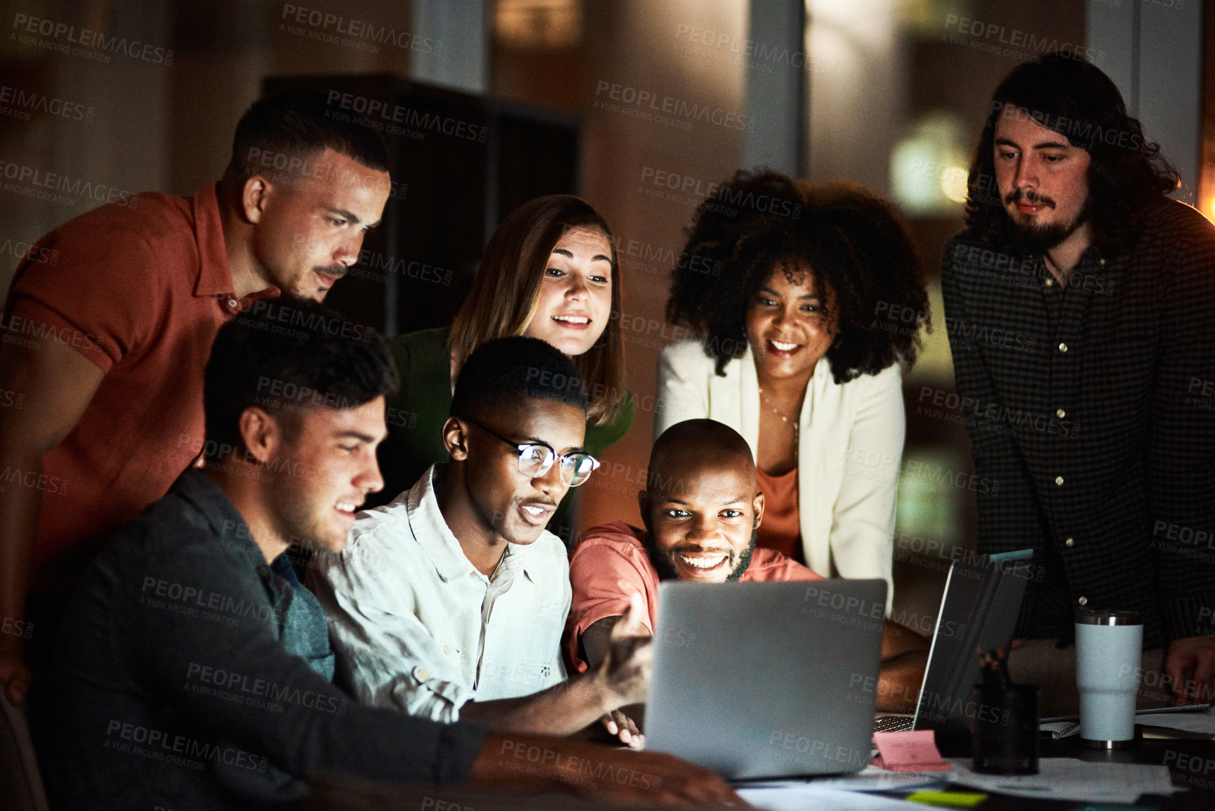 Buy stock photo Shot of a group of designers looking at something on a laptop while working late