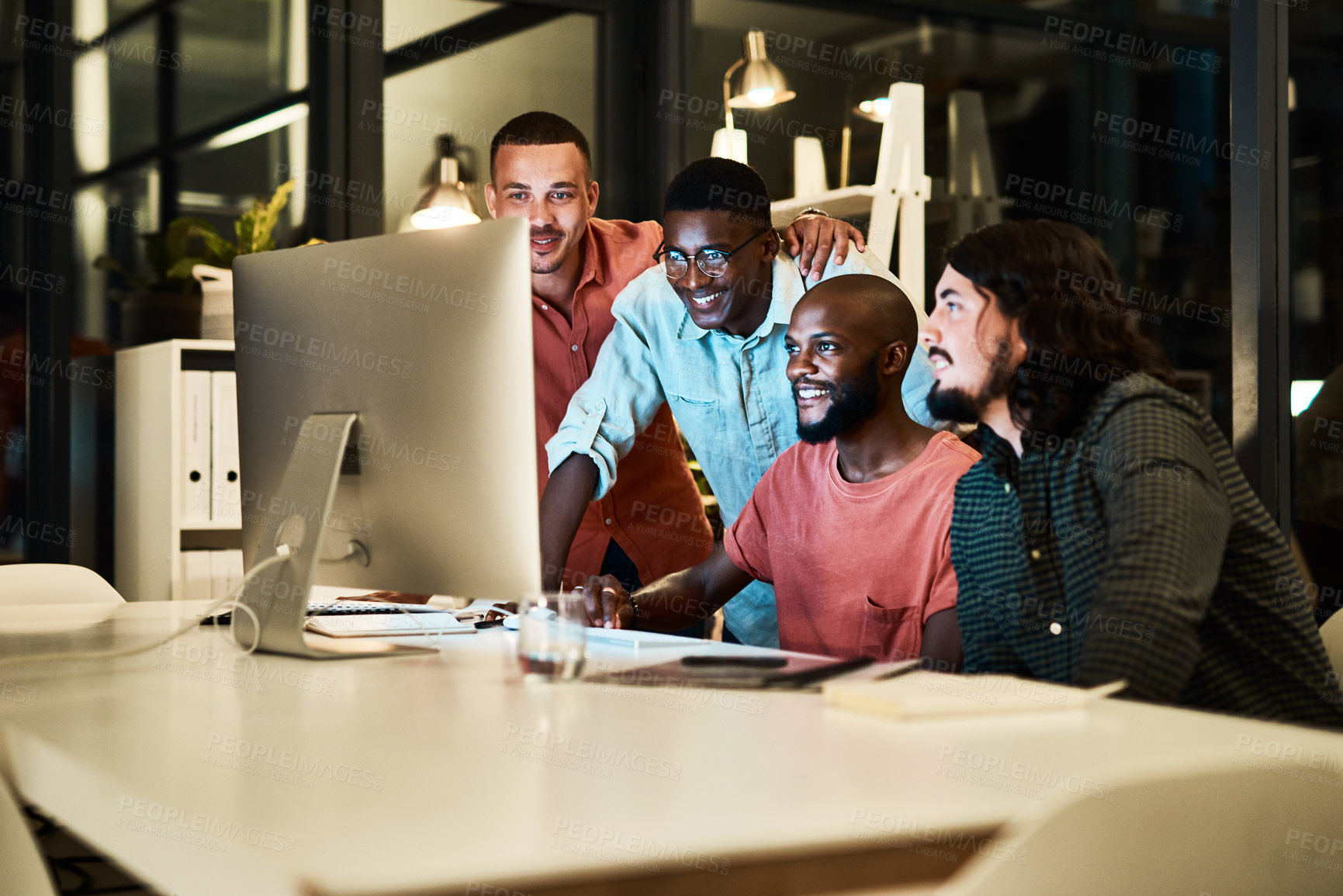Buy stock photo Shot of a group of designers looking at something on a computer while working late