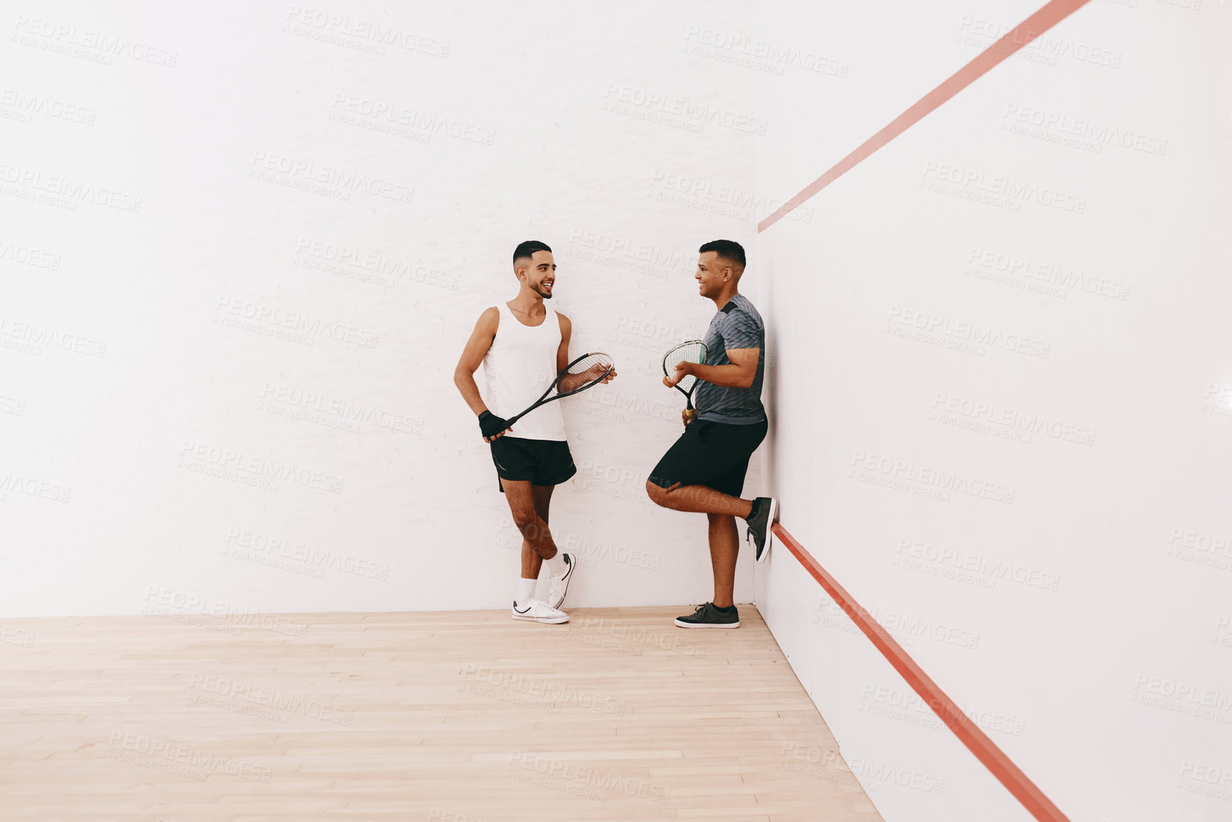 Buy stock photo Shot of two young men chatting after playing a game of squash