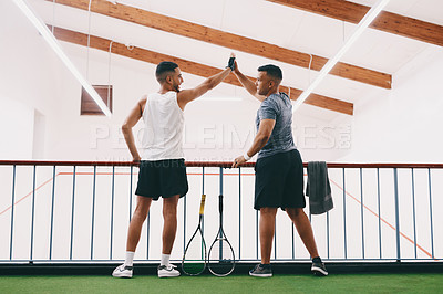 Buy stock photo Rearview shot of two young men celebrating while watching a game of squash from the viewing gallery