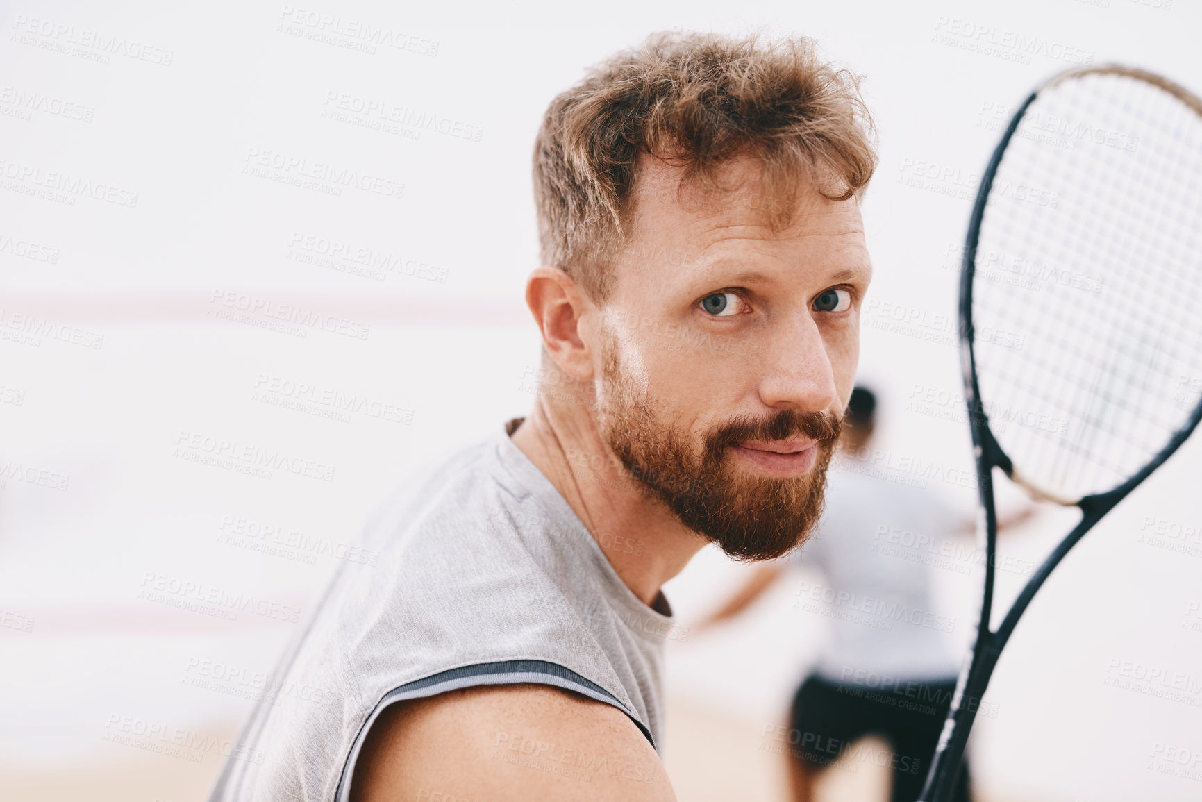 Buy stock photo Portrait of a young man playing a game of squash with his team mate in the background