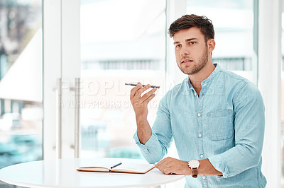 Buy stock photo Cropped shot of a handsome young businessman recording a voice note while siting at a table in his office