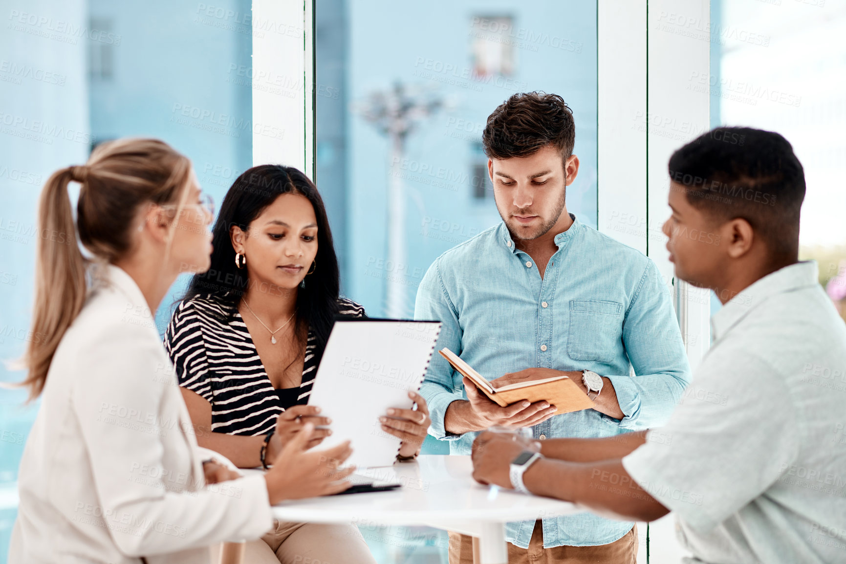 Buy stock photo Cropped shot of a group of young business colleagues sitting around a table in their office