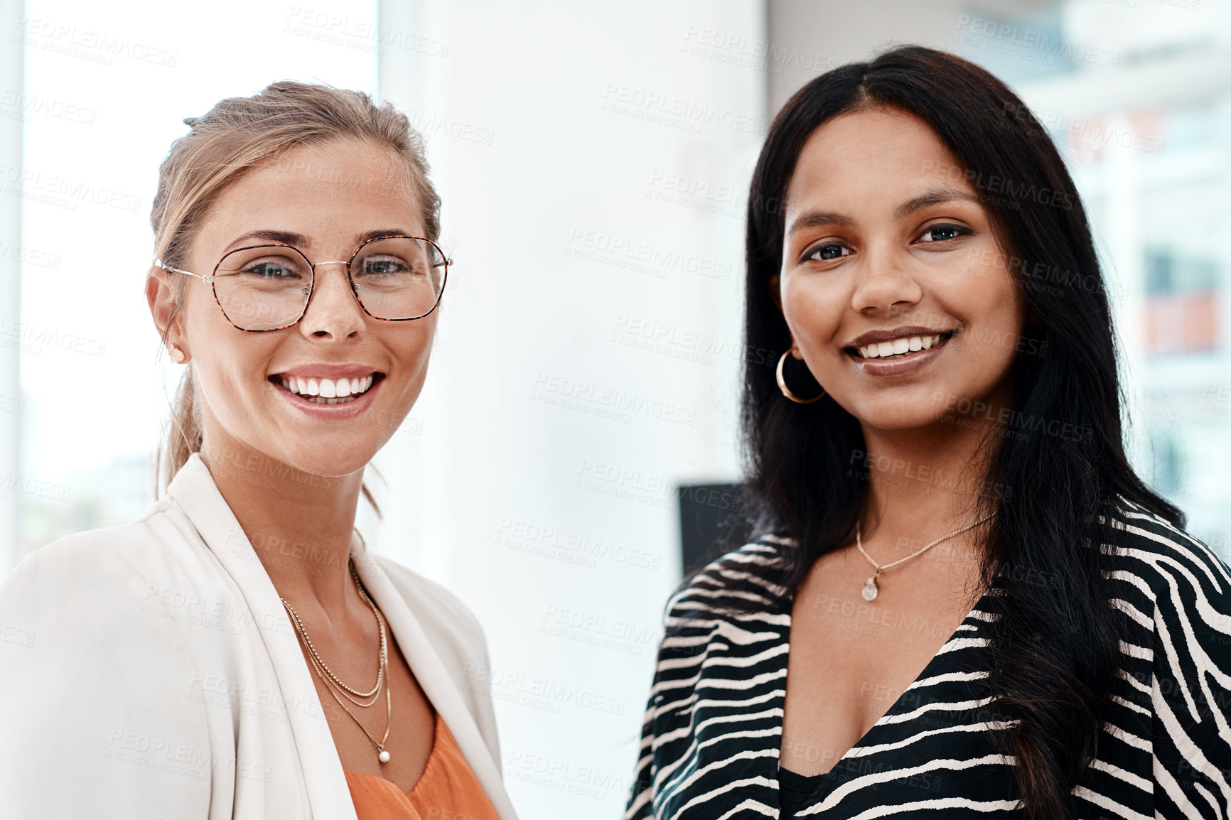 Buy stock photo Cropped portrait of two attractive young businesswomen standing in their office