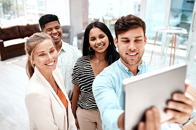 Buy stock photo Cropped shot of a group of young business colleagues taking selfies with a tablet in their office