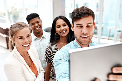 Buy stock photo Cropped shot of a group of young business colleagues taking selfies with a tablet in their office