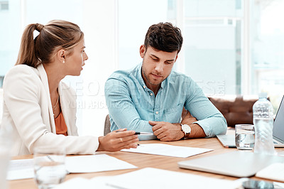 Buy stock photo Cropped shot of two young business colleagues going over some documents in the boardroom