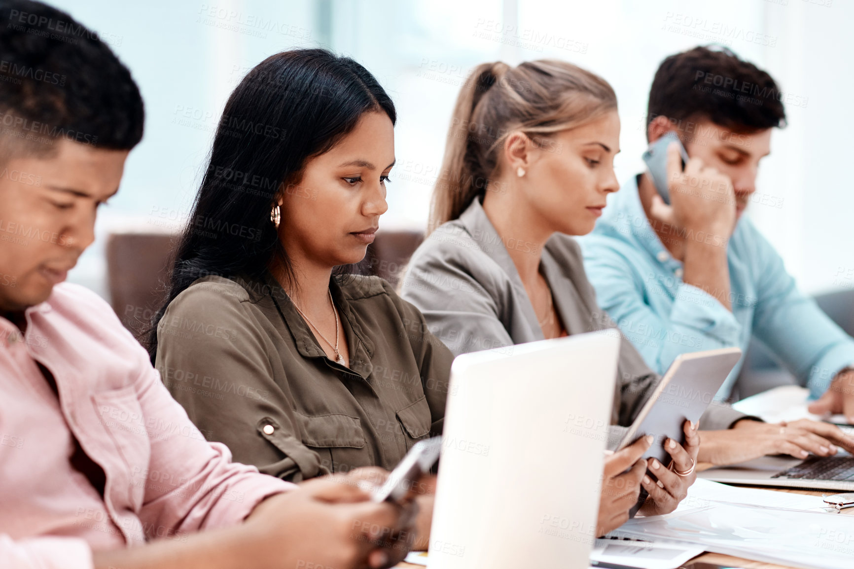 Buy stock photo Cropped shot of a group of young business colleagues sitting in a row at a table in the boardroom